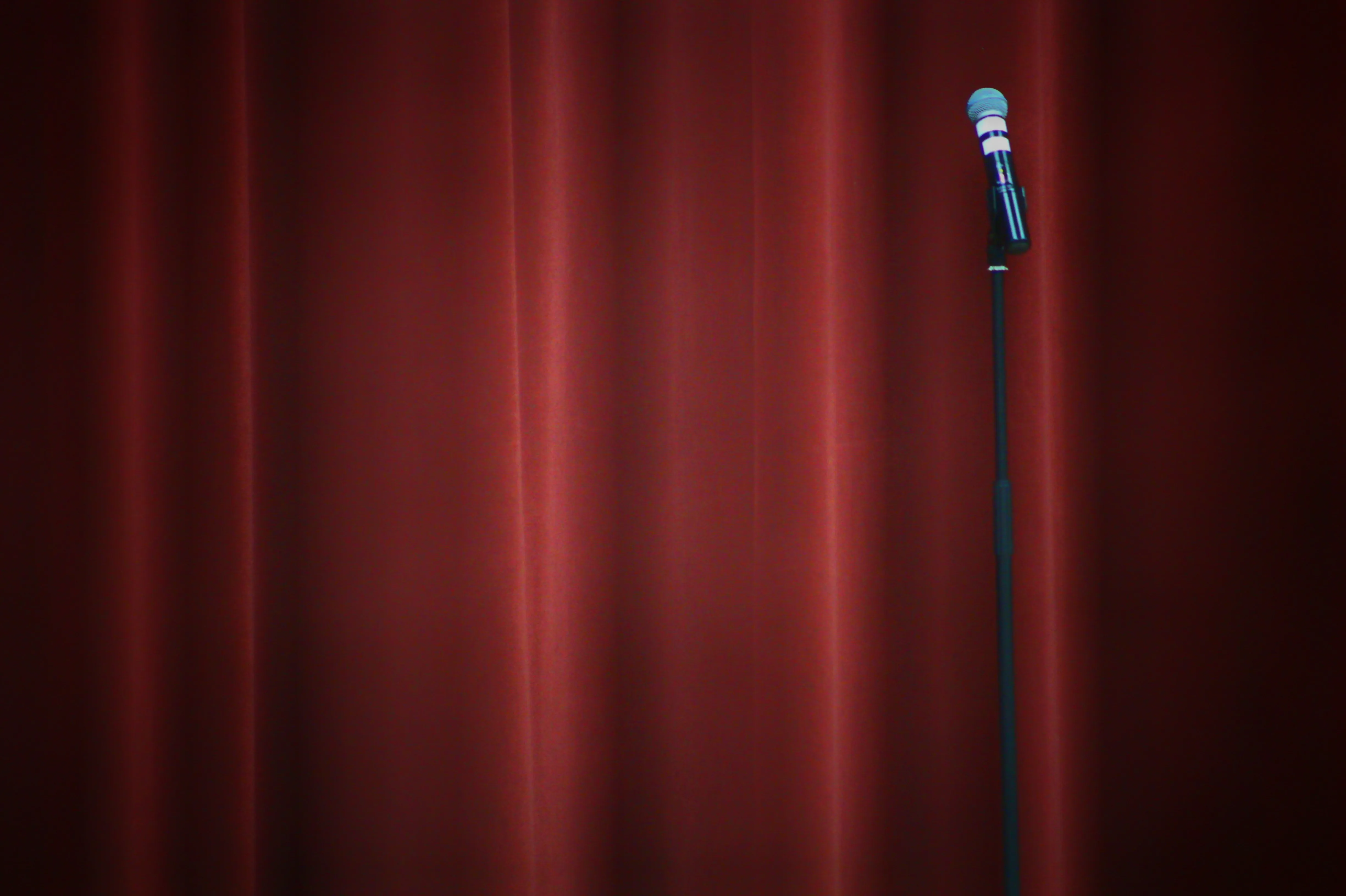 Stand-up comedy stage with microphone on red curtain