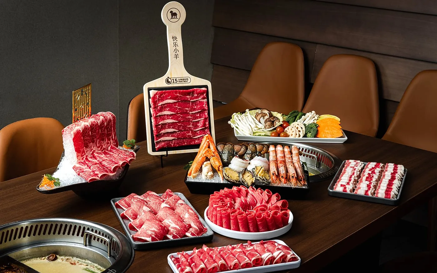 Happy Lamb Hot Pot table with broth, sliced meats, vegetables, and dipping setup for communal dining