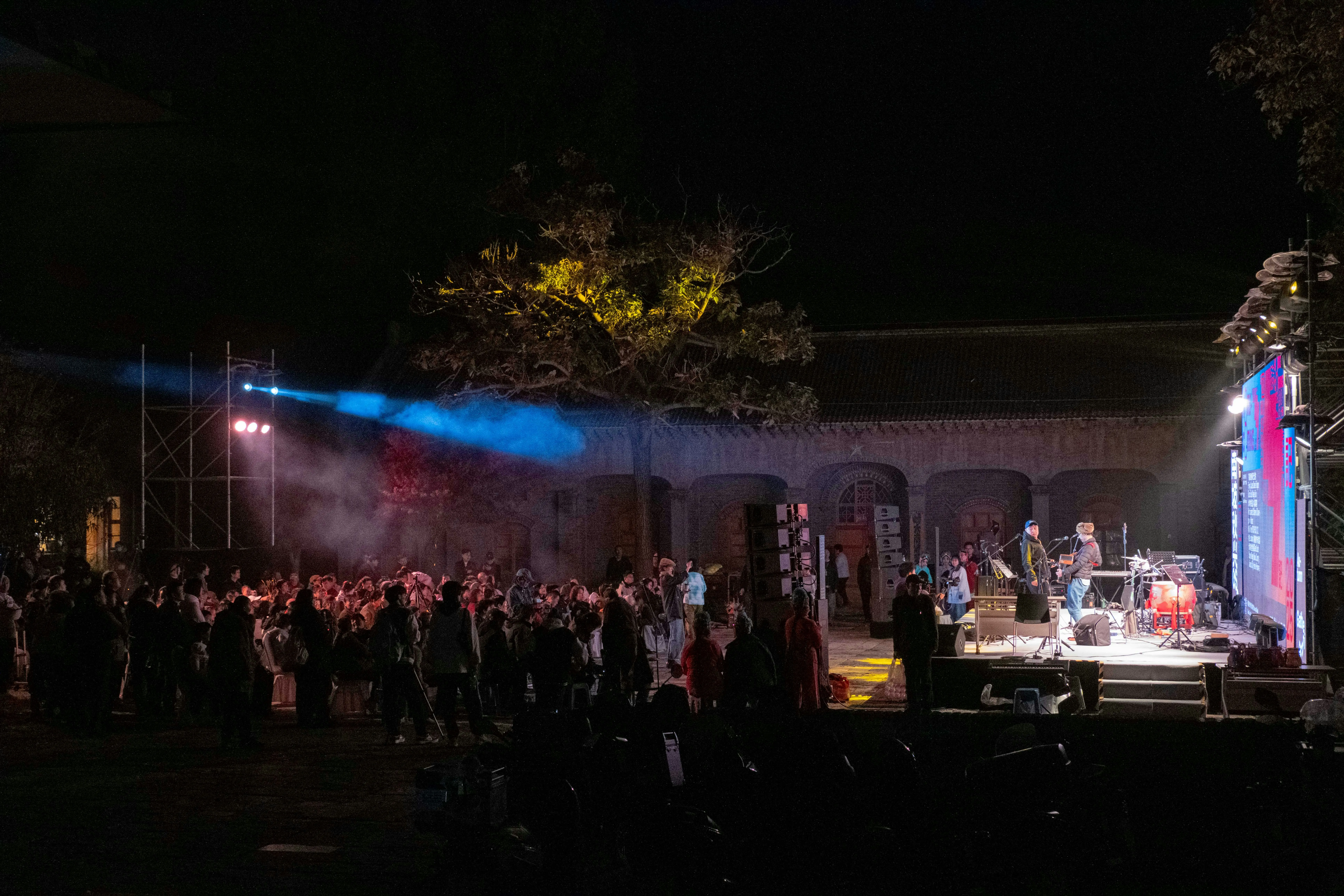Outdoor comedy festival stage with a lively crowd at dusk
