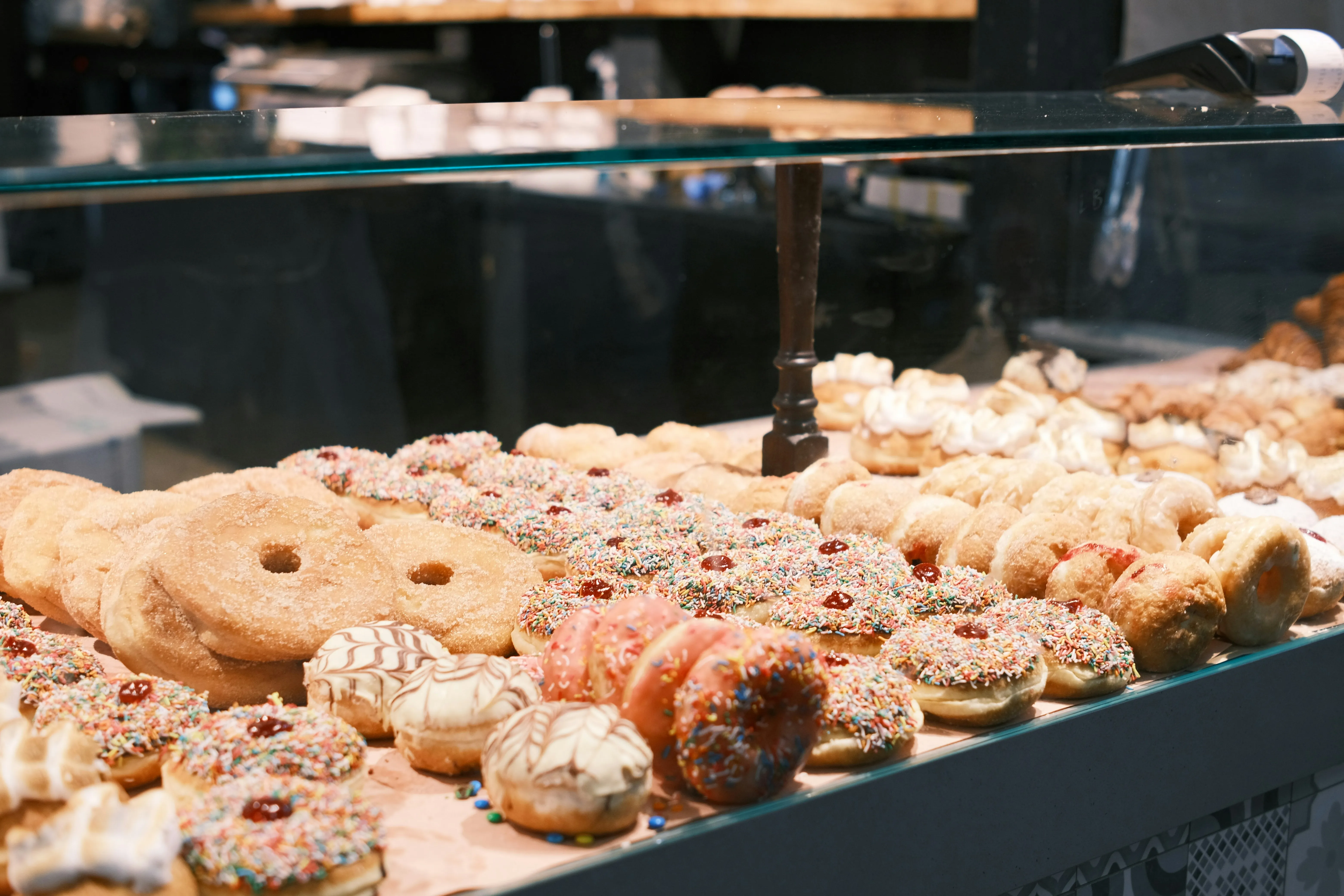 Assorted donuts in a glass display case with colourful glazes and toppings