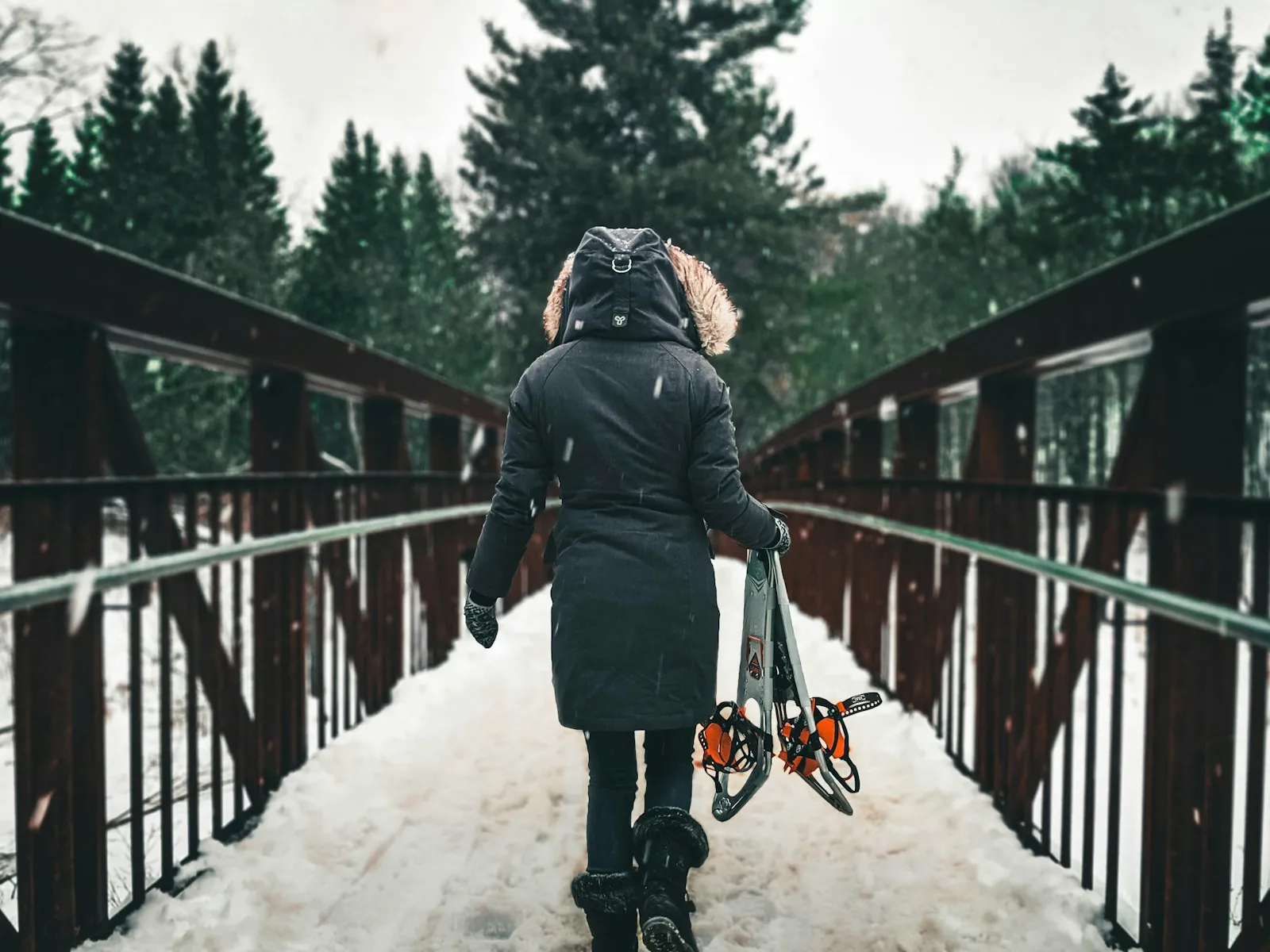Person walking on a snow-covered bridge in winter.