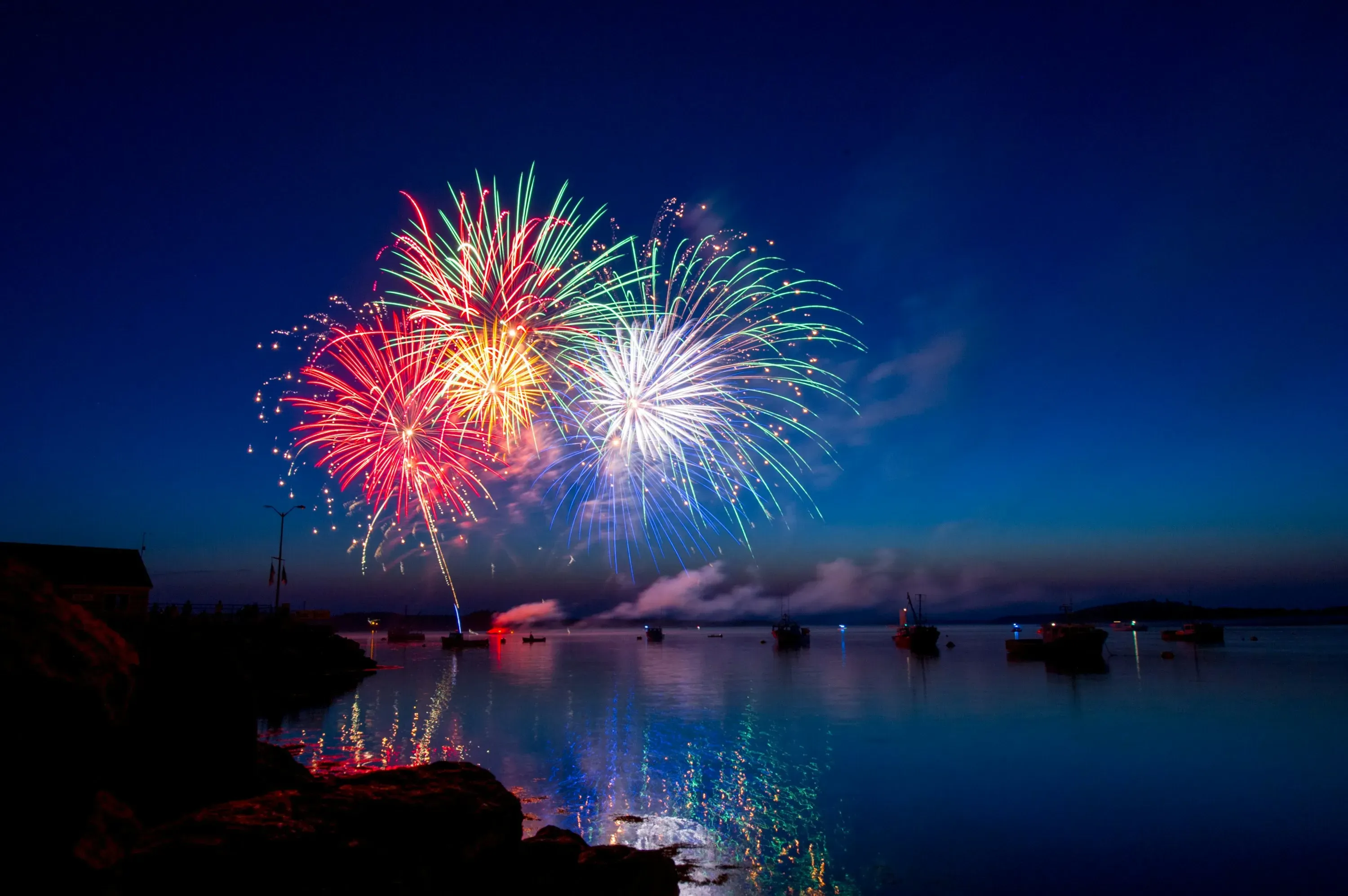 Spectacular fireworks display lighting up the night sky over water.