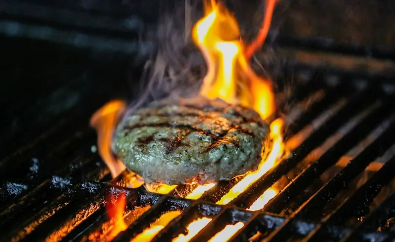 Flame-grilled burger on a grill with flames