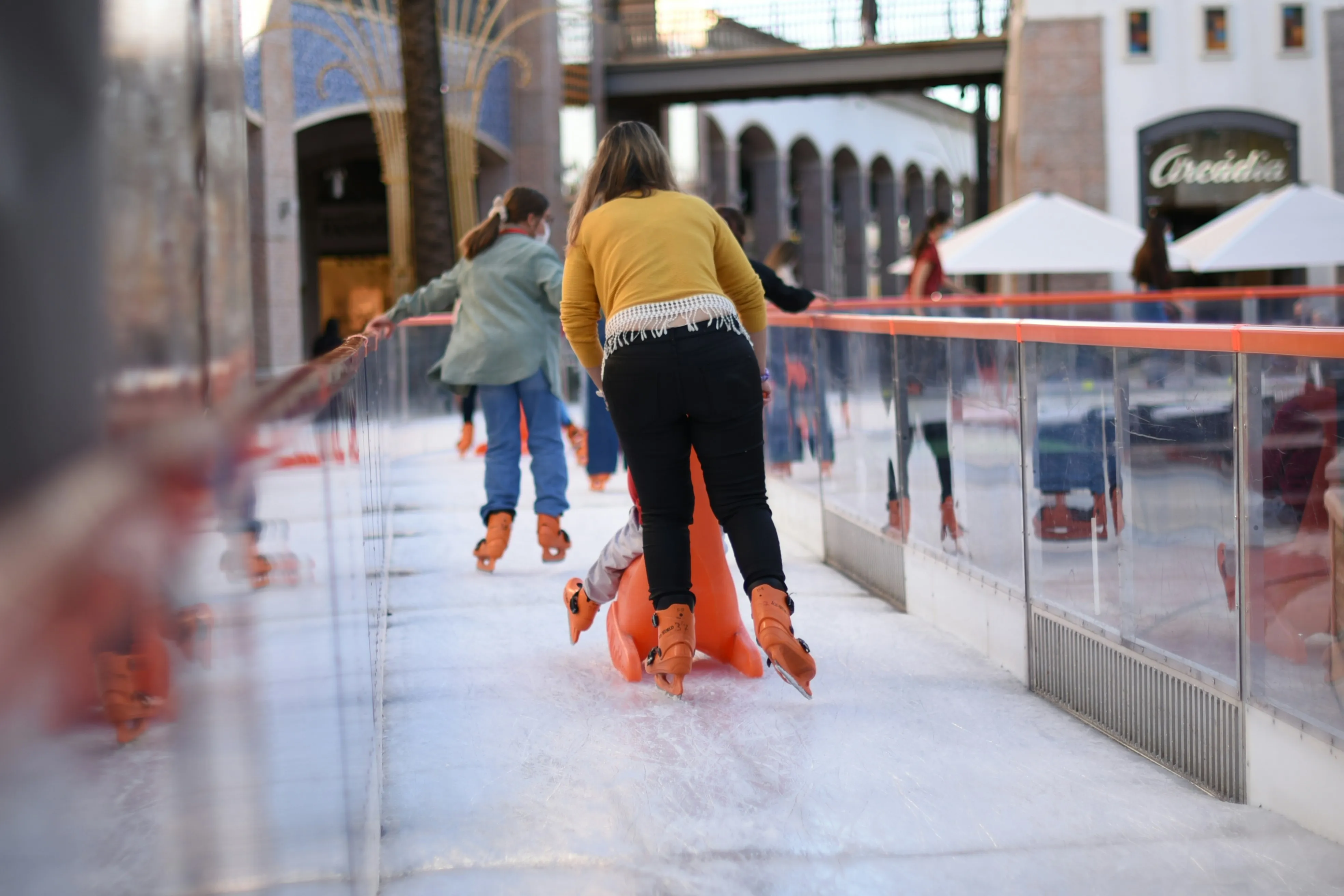 A well-bundled skater wearing warm layers, gloves, and a toque smiling on Ottawa's outdoor rink on a clear winter day
