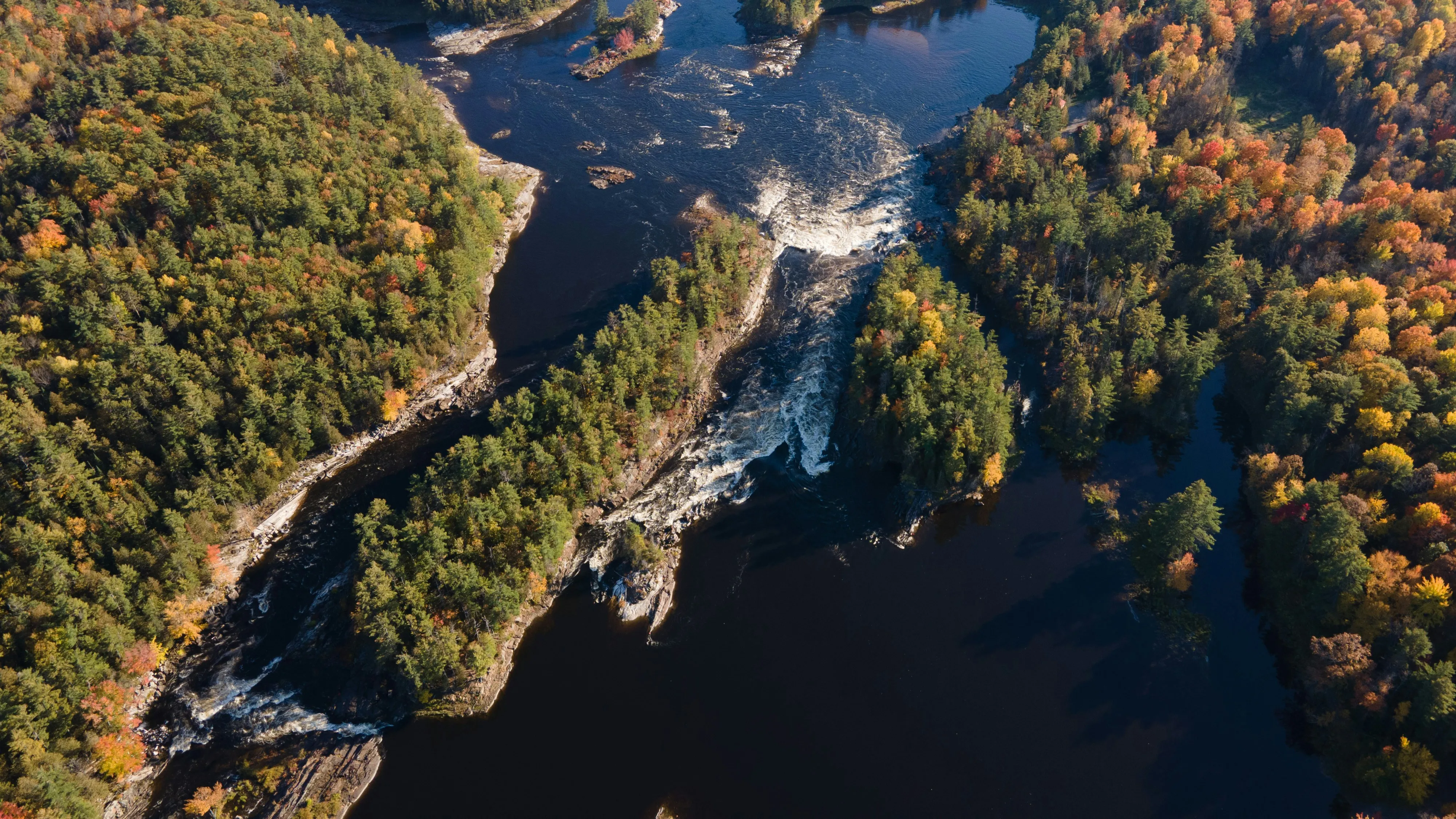 Kayak on a calm river beneath dramatic rock formations and trees