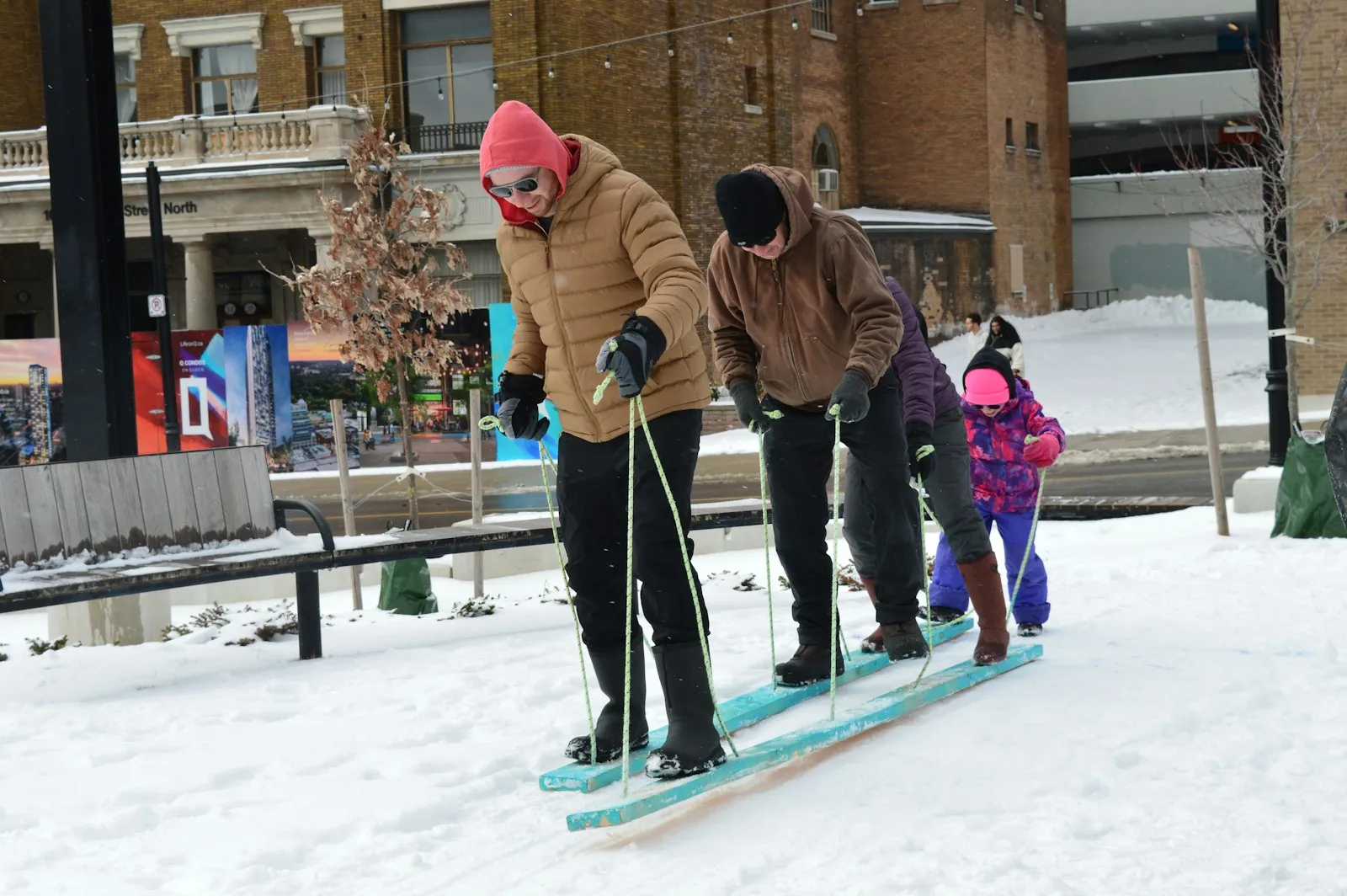 Families sledding on a snowy hill.