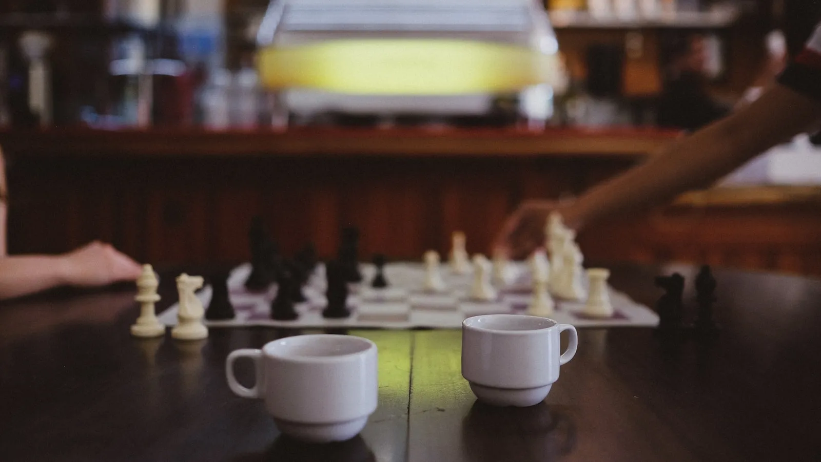 Coffee cups and a chess game at a cafe table