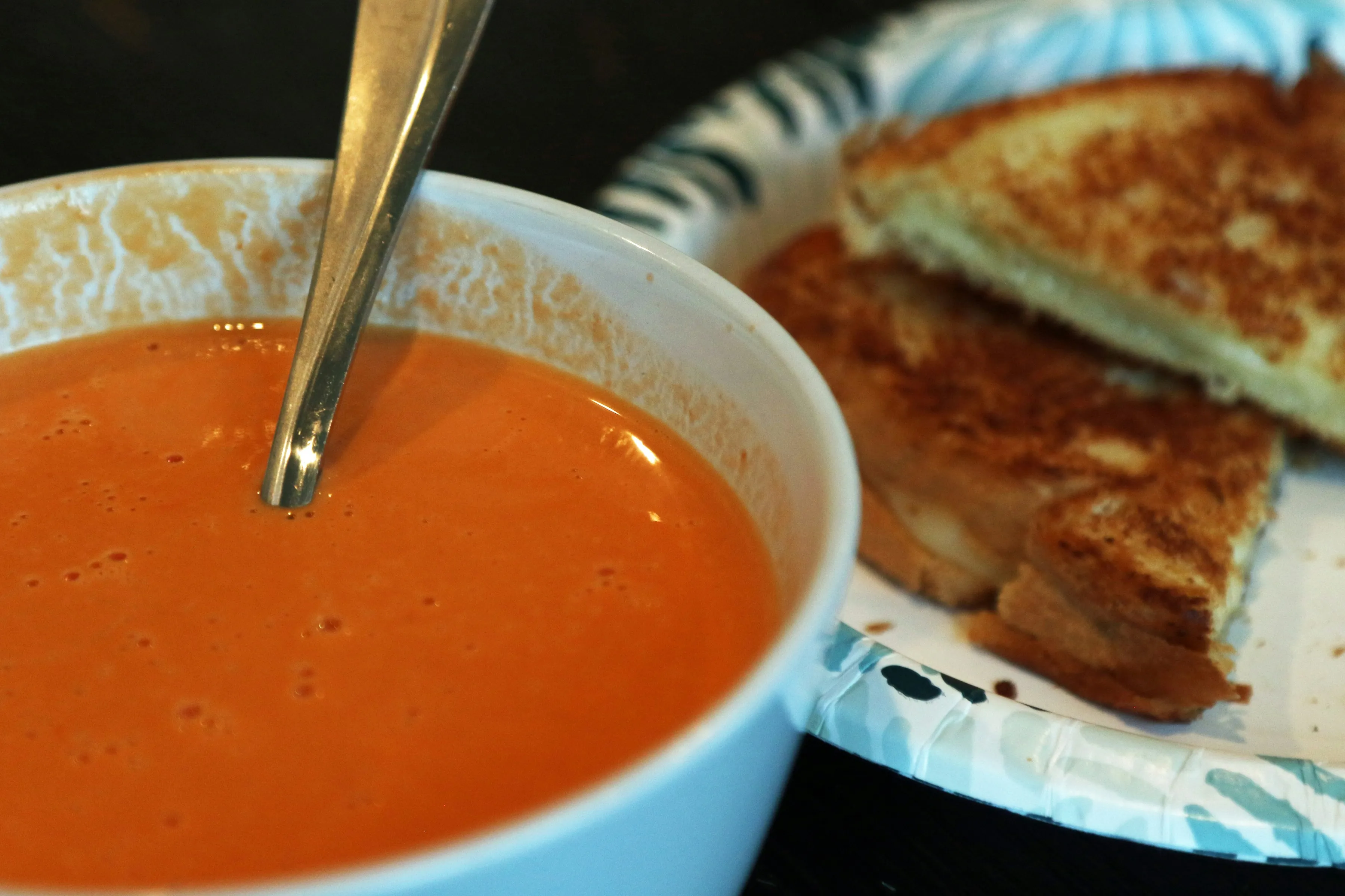 Grilled cheese sandwich dipping into tomato soup