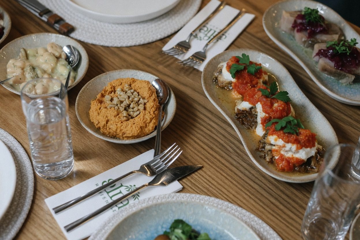 Mediterranean dinner table with grilled fish, dips, bread, and cocktails