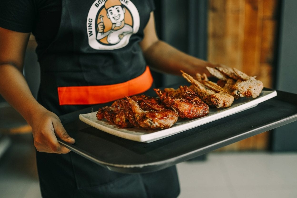 Plated wings being carried out from a pub kitchen