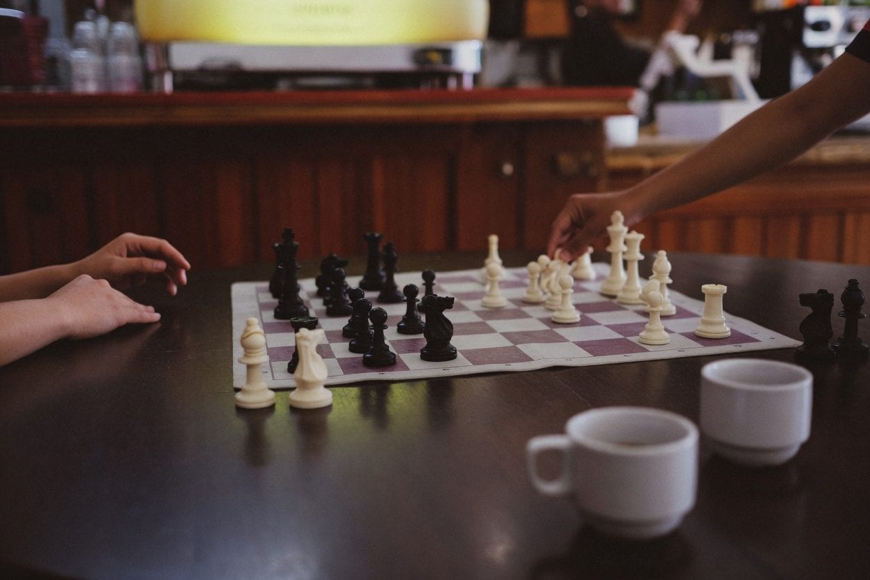 Coffee cups and a chess game at a cafe table