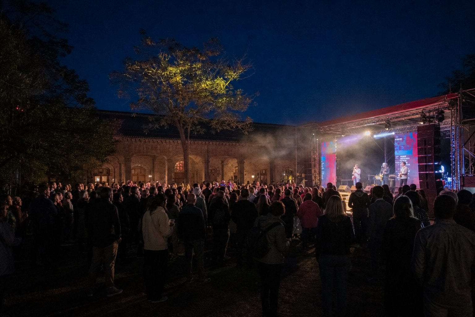 Outdoor comedy festival stage with a lively crowd at dusk