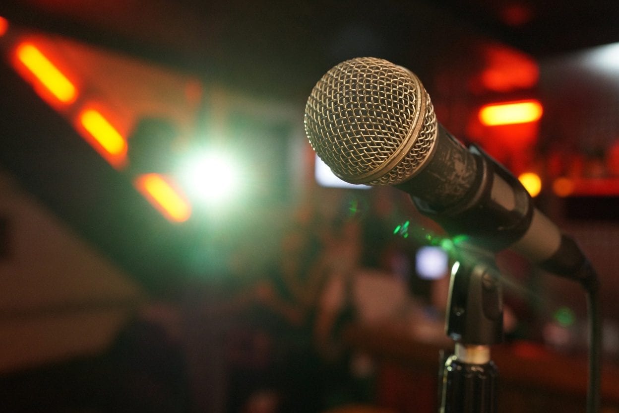Microphone on a lit comedy stage with dramatic lighting