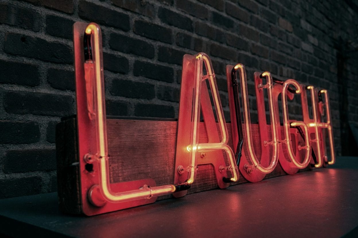 Neon "Laugh" sign in a dimly lit comedy venue