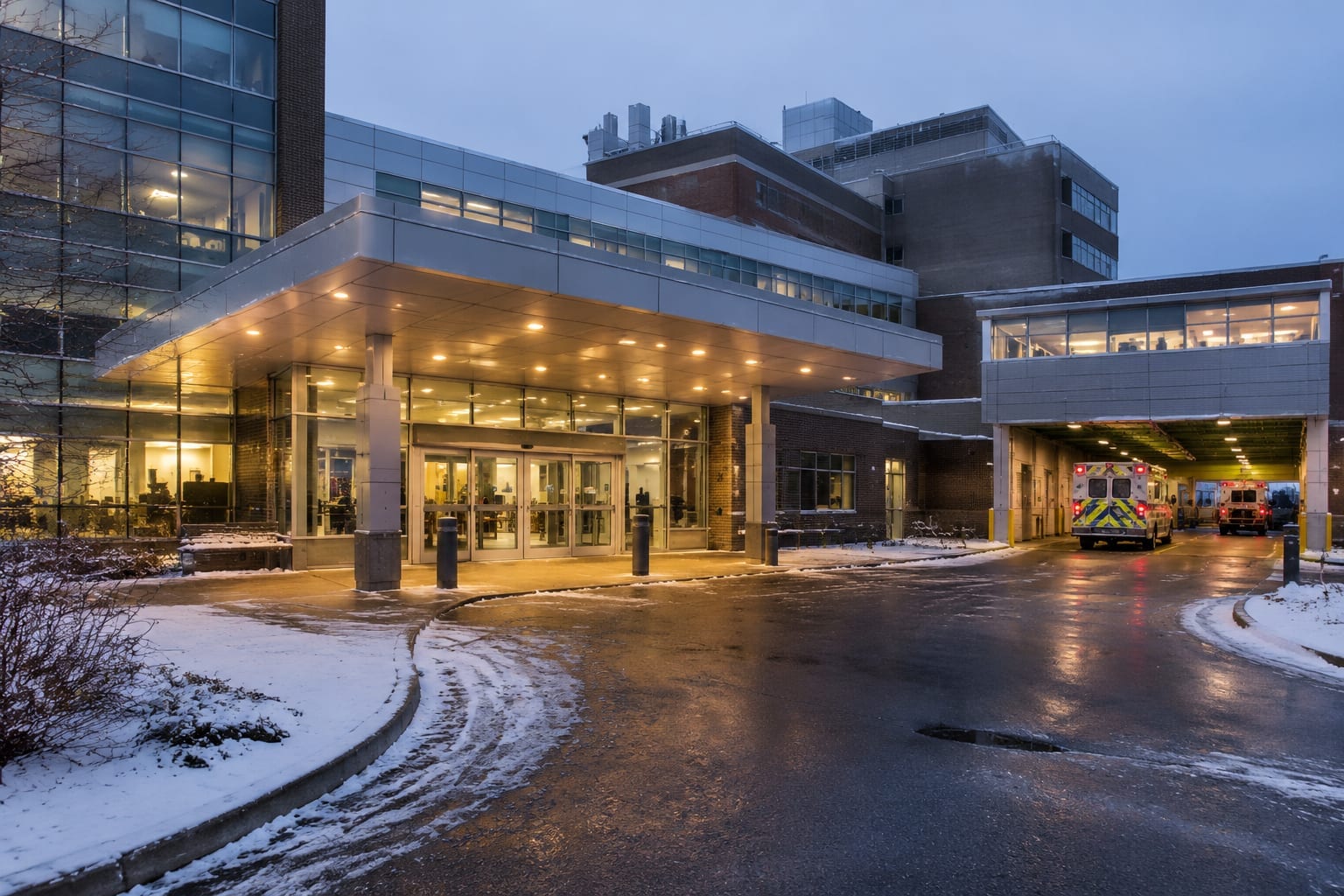 The exterior of a hospital emergency entrance at dusk with a lit canopy