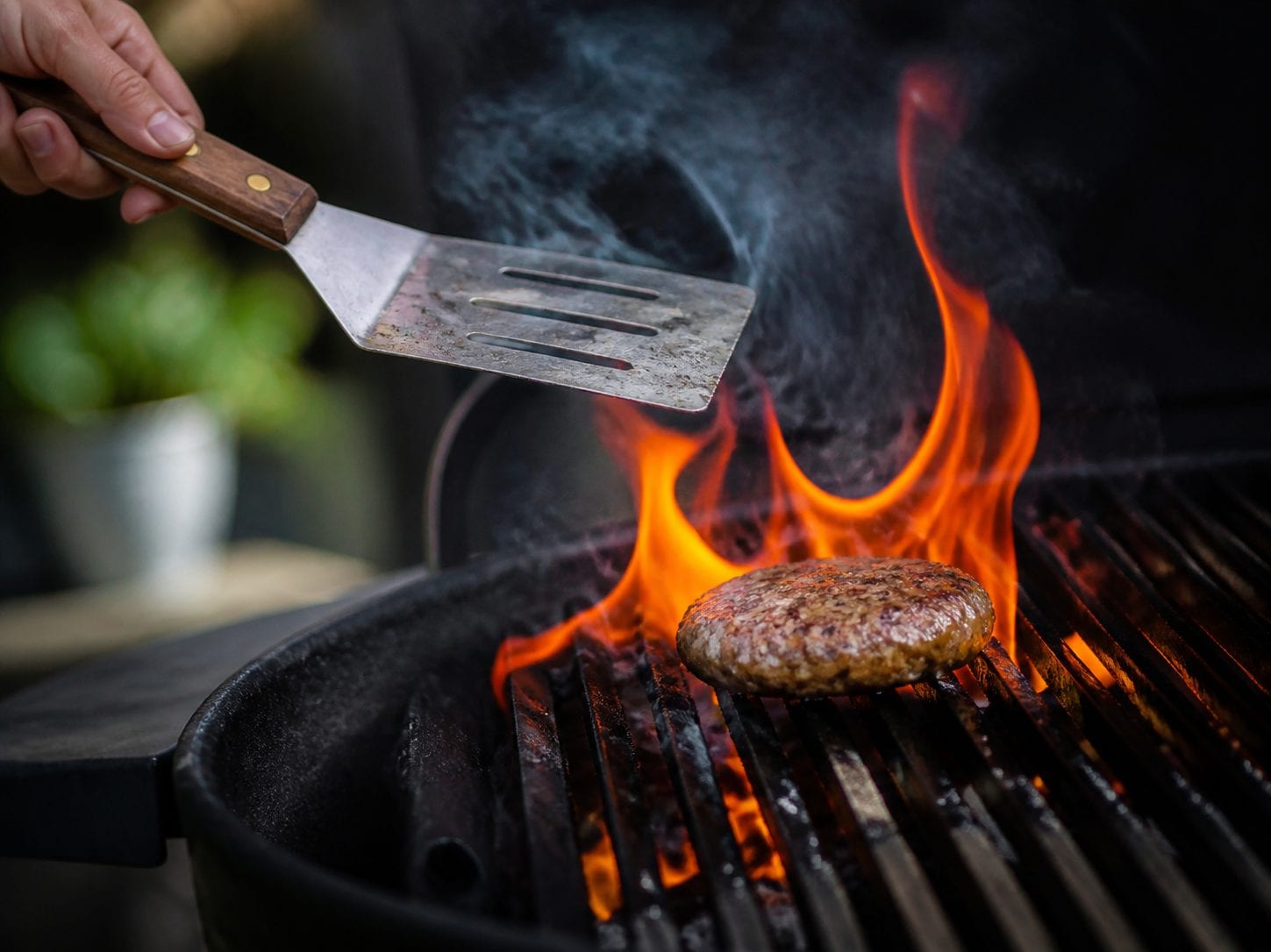 Flame-grilled burger on a grill with flames