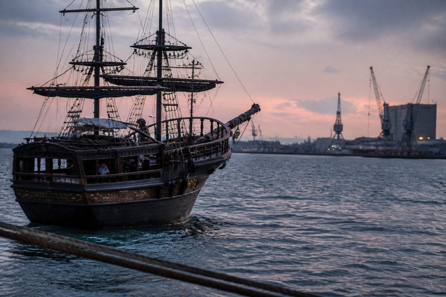 A pirate ship on the water at twilight — evoking the nautical mystery of The Pirate's Code