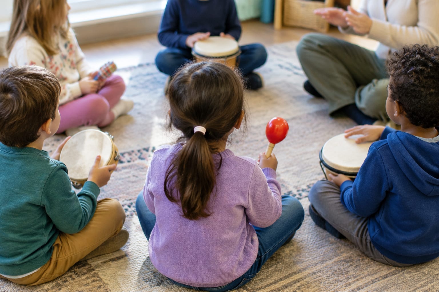 Young children in a circle playing hand percussion in a community room