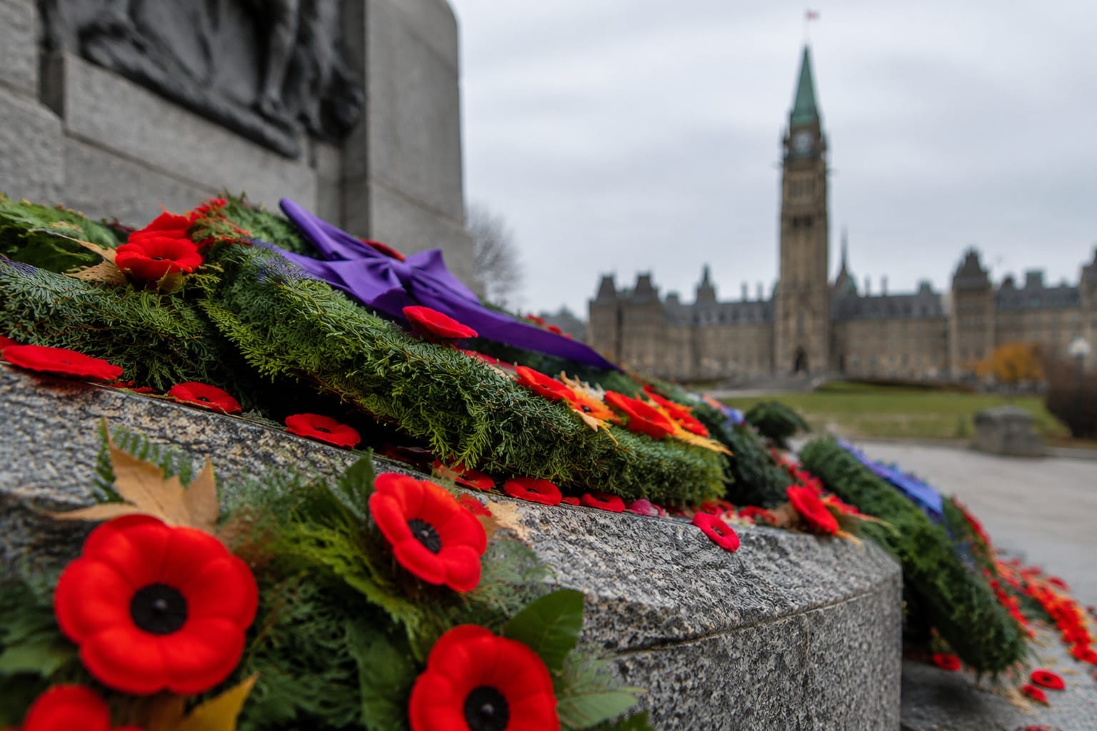 Red poppies and wreaths laid on a granite tomb at a war memorial on a cold morning