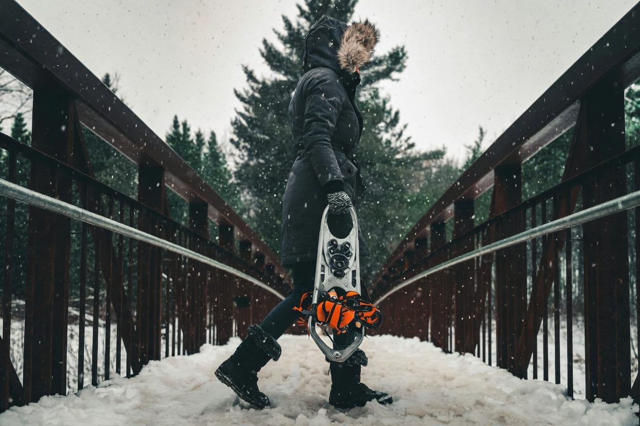 Person walking on a snow-covered bridge in winter.