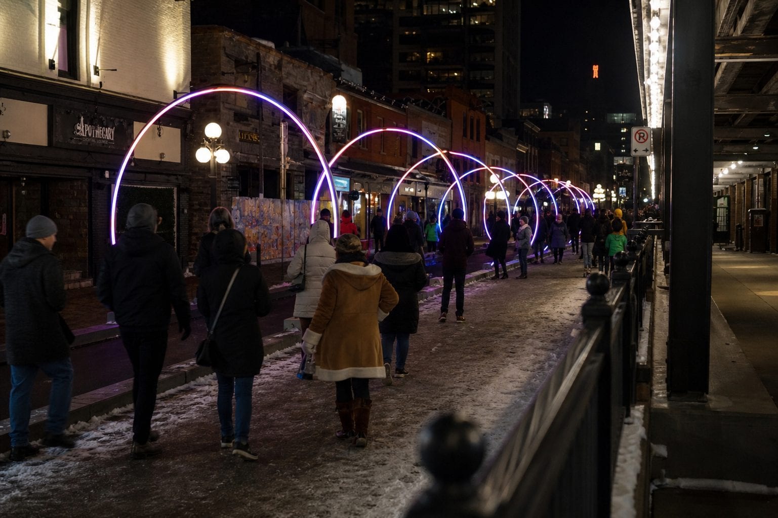 People walking on a snowy Ottawa street at night.