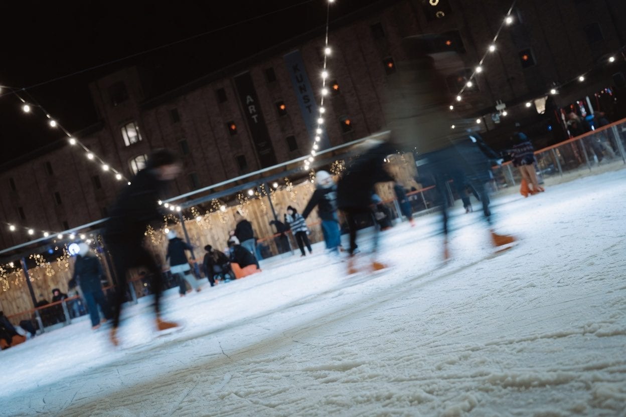 People skating at an outdoor rink at night.