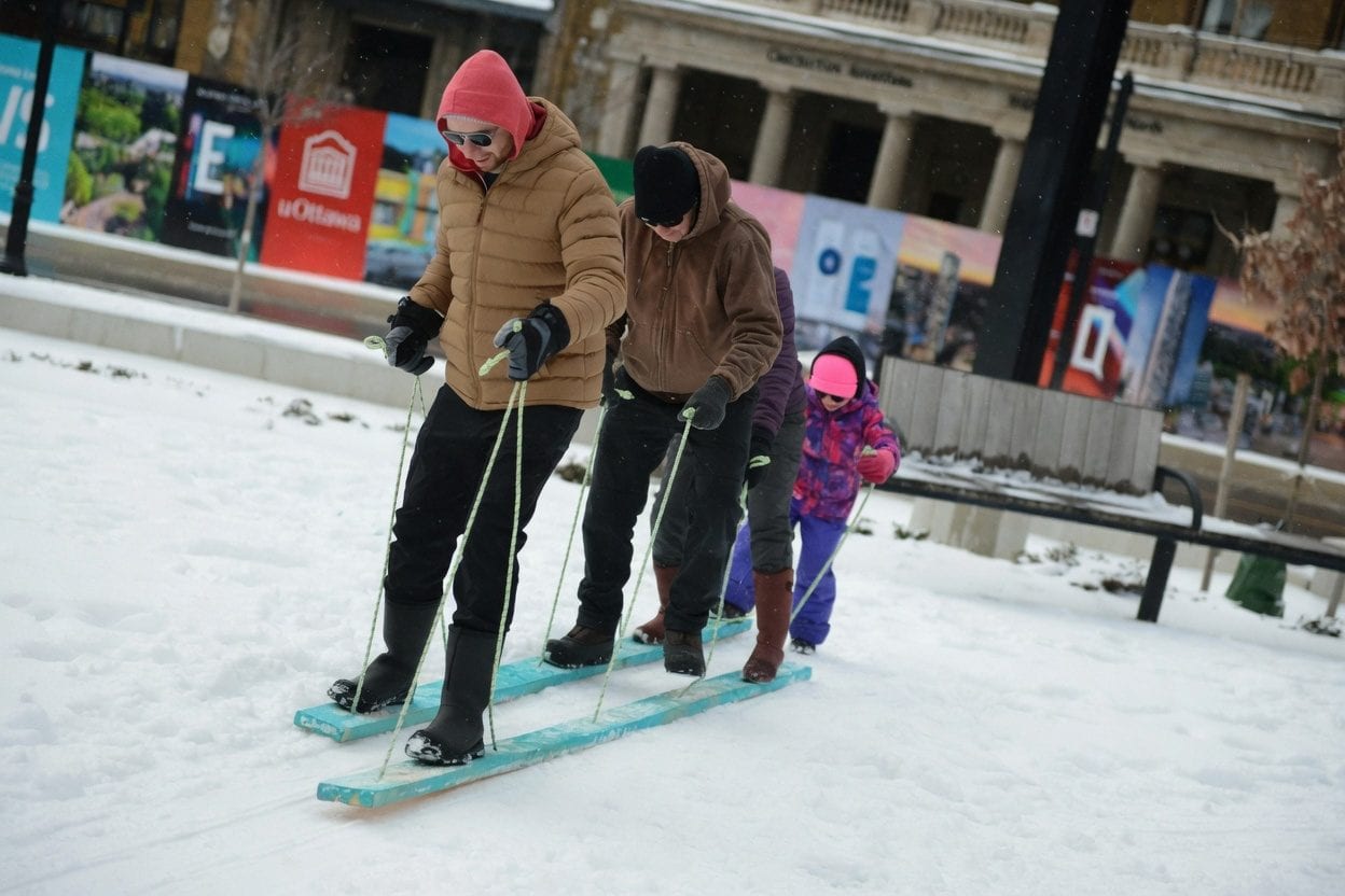Families sledding on a snowy hill.
