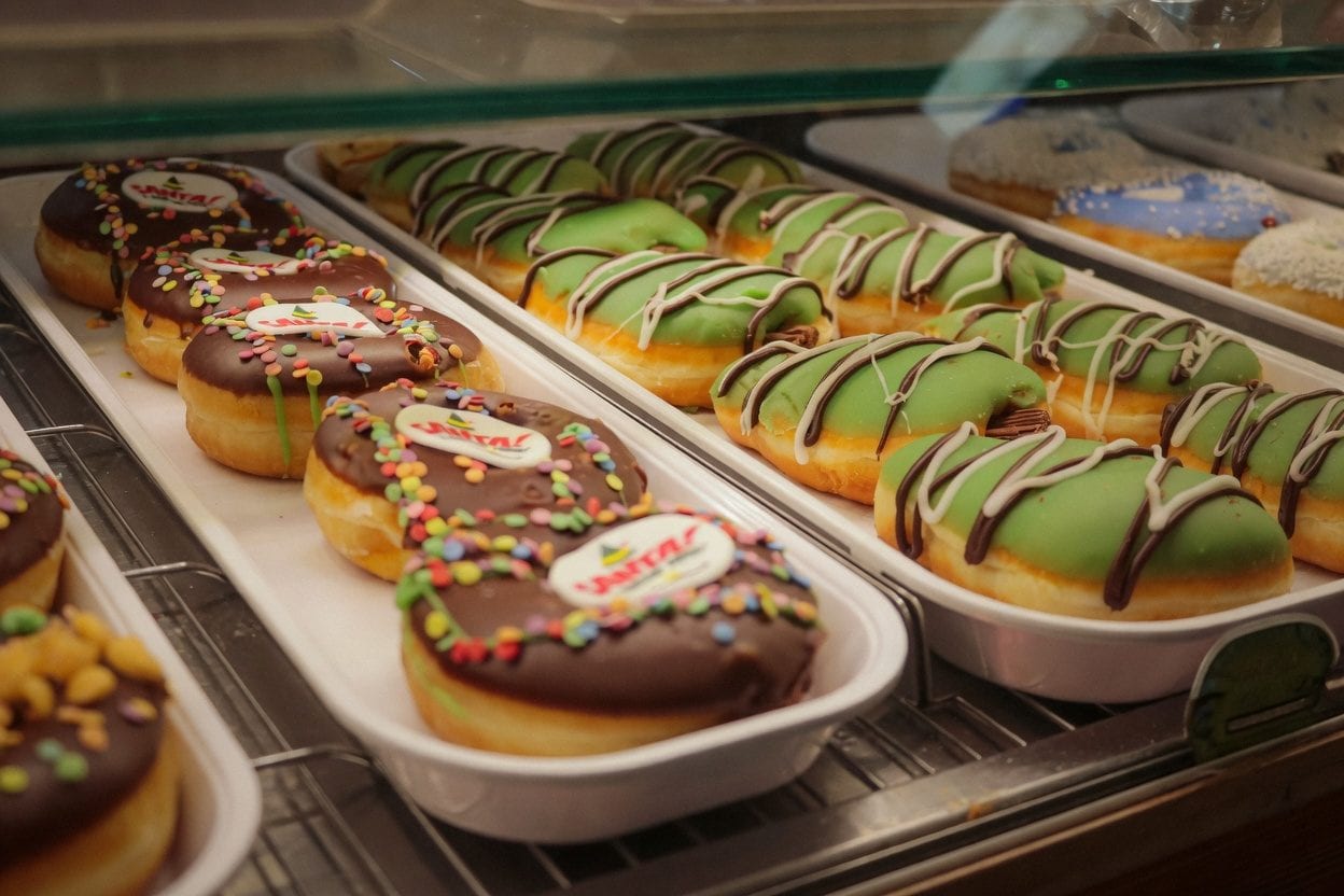 Colorful donuts in a display case with bright glazes and toppings