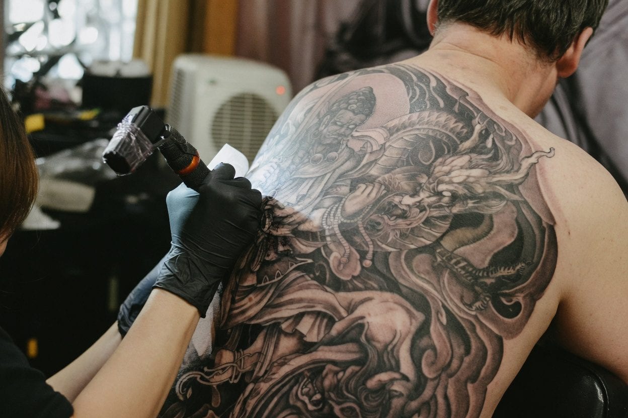 Tattoo artist working on detailed piece