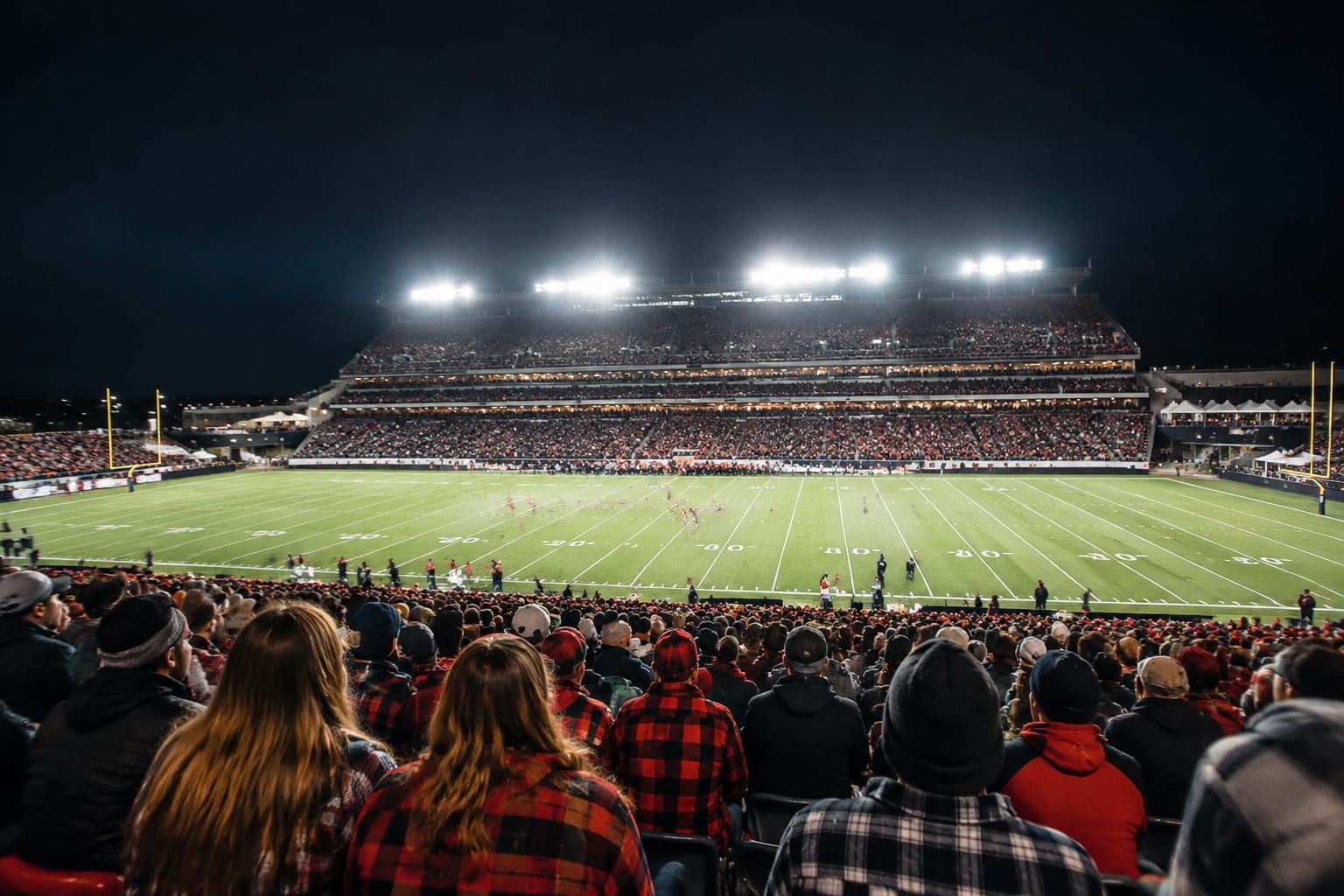 Packed stadium stands under the lights during a Friday night football game