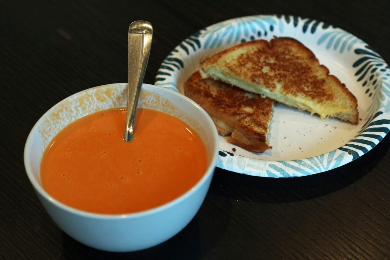 Grilled cheese sandwich dipping into tomato soup