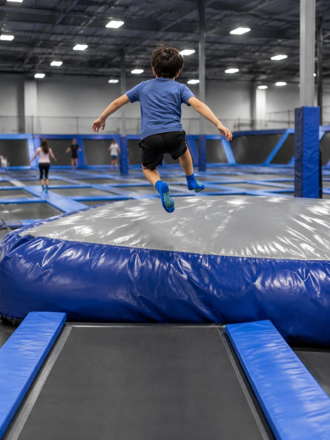Child jumping from a trampoline onto an inflatable air-bag crash pad indoors